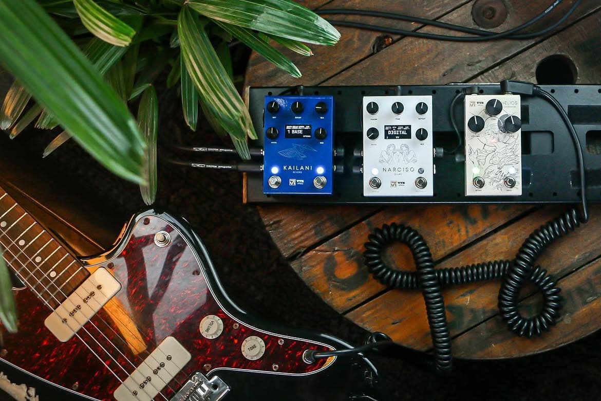 Pedalboard com Kailani, Narciso e outro pedal da Gold Series, ao lado de uma guitarra