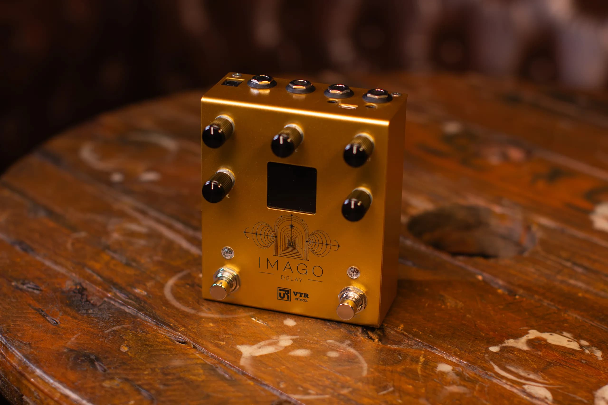 Imago Delay sobre uma mesa de madeira, com os conectores no topo do pedal